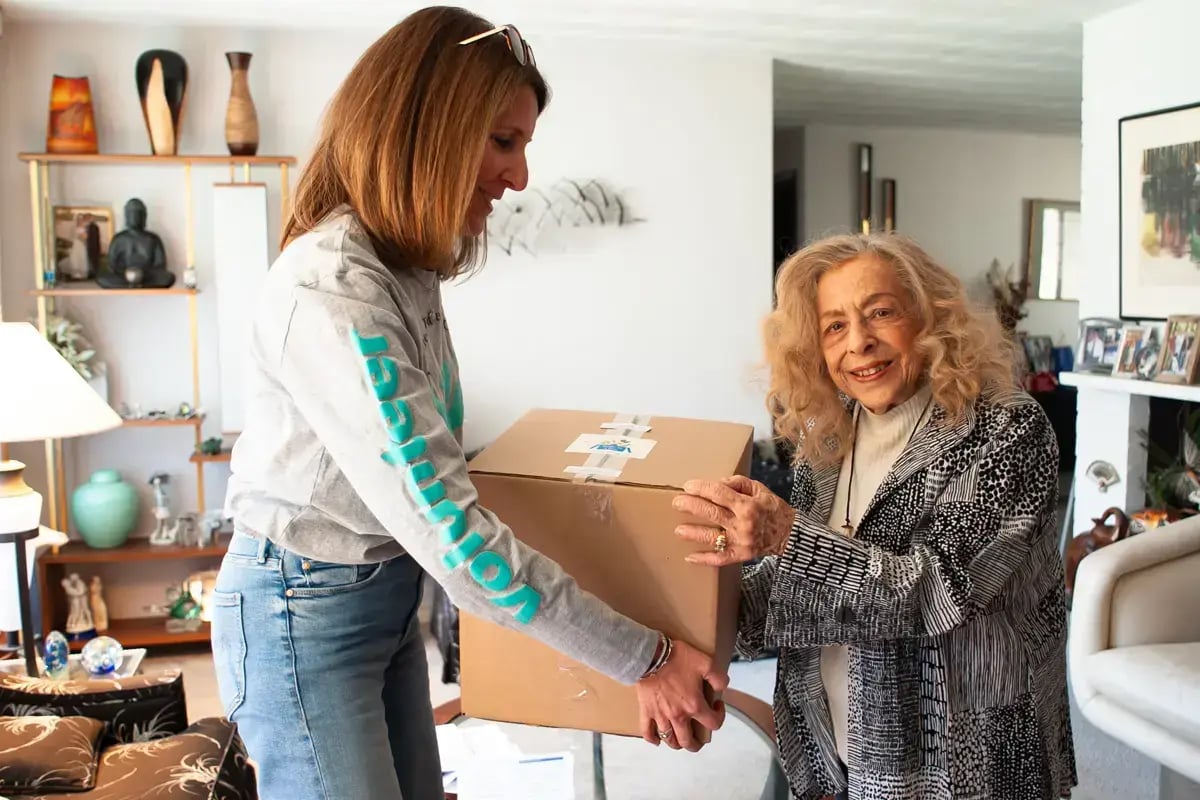 Community member providing a food box to an older adult, symbolizing compassionate care and giving to CJP in the Greater Boston Jewish community.