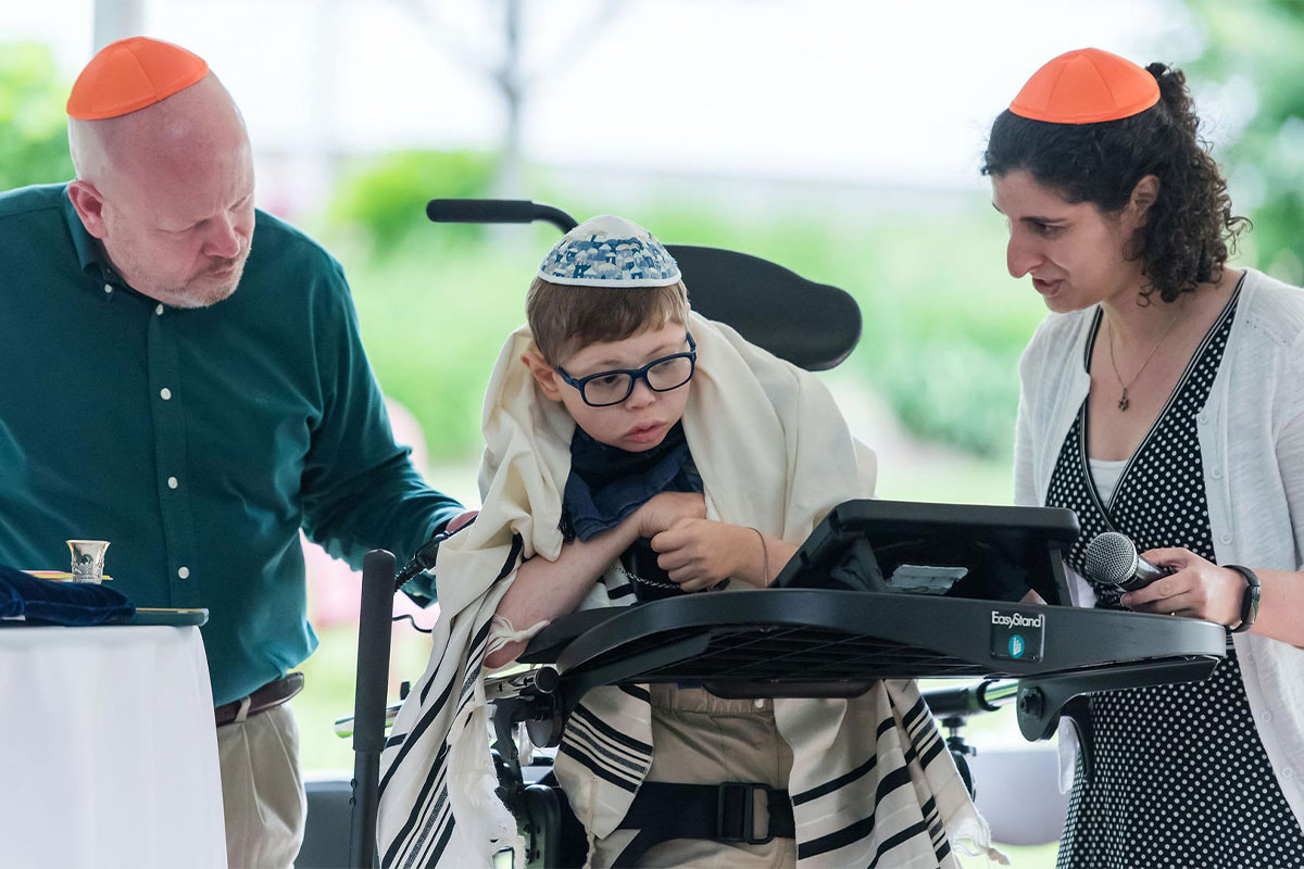 Jewish Community Safety Boston inclusive religious ceremony with a child wearing a tallit and kippah supported by family members, reflecting care, accessibility, and a strong Jewish community in Greater Boston.