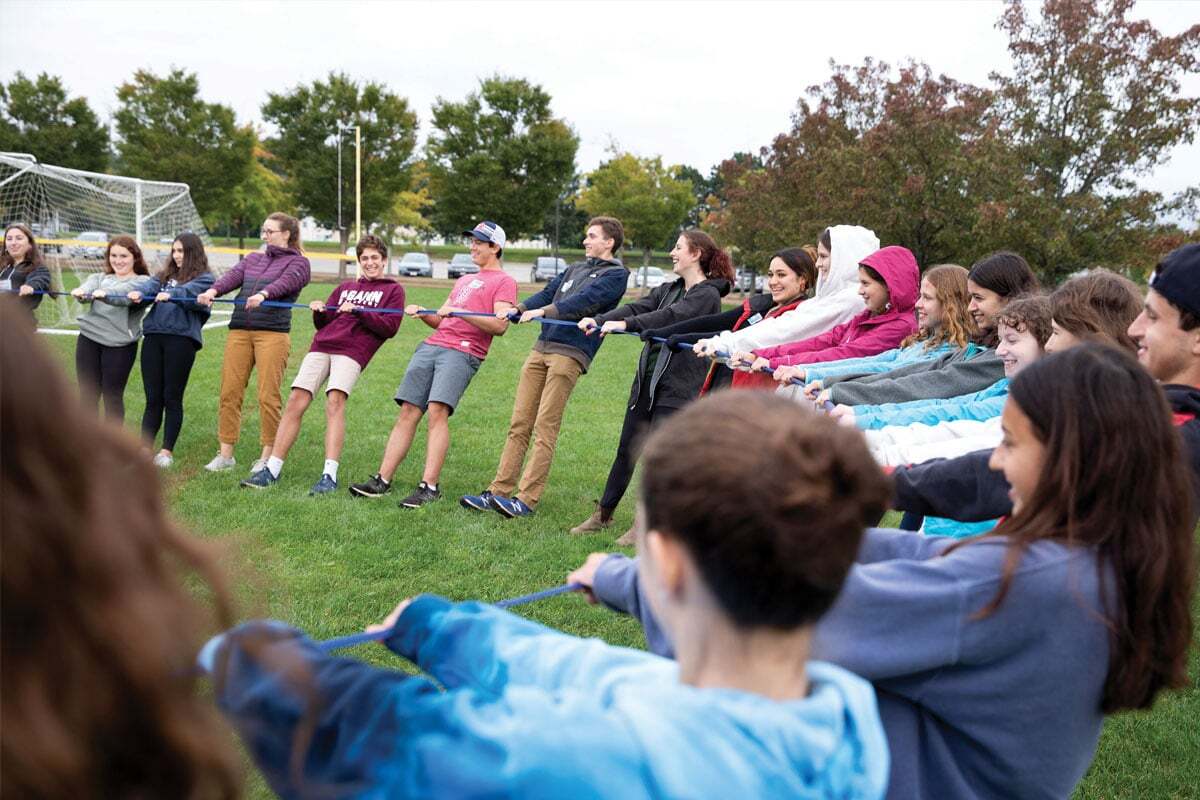 Jewish life Boston youth engagement with teens participating in a tug-of-war game on a grassy field, highlighting connection leadership, and community for babies to teens in Greater Boston.