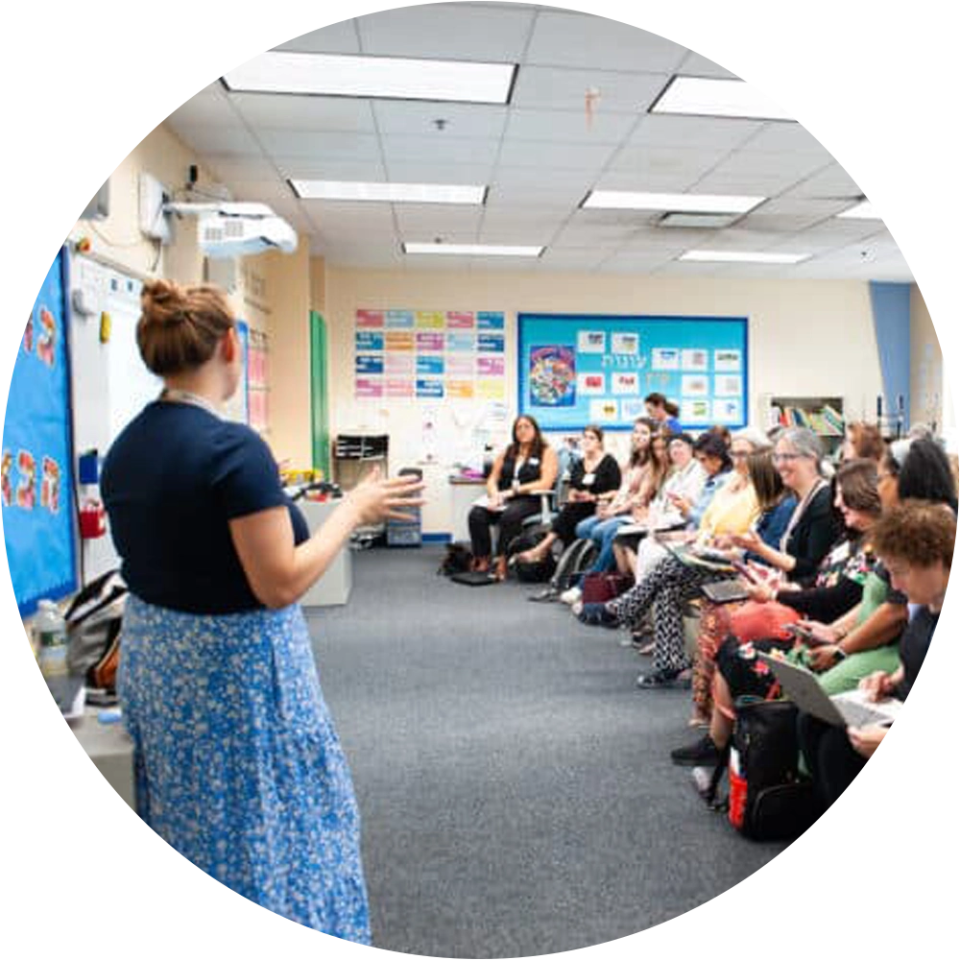 A teacher leads a group of educators in a Boston Jewish day school classroom, sharing ideas and collaborating during a Stronger Together professional development session.